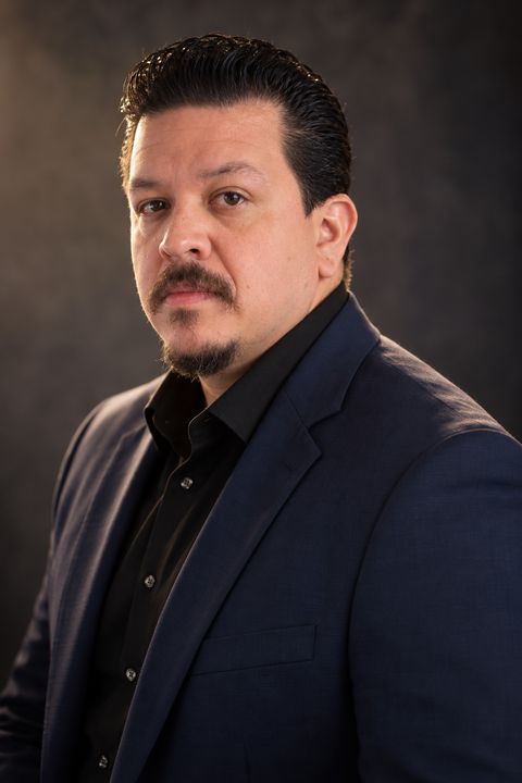 Antonio Cardona con blazer azul marino y camisa negra, agente inmobiliario en Miami con RE/MAX City Centre Realty